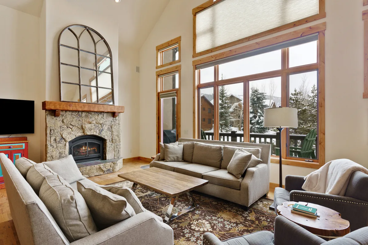 A warm and inviting interior living space is showcased here, with a large fireplace, expansive windows, and comfortable seating, suggesting a cozy retreat after a day of outdoor activity.