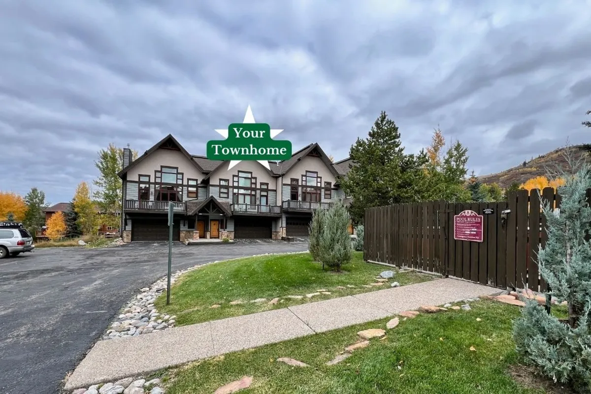 This image features the townhouse facade with clear views of the landscaped yard, prominent entryway, and signage. The inviting scene also hints at the proximity of walking paths and the neighborhood's outdoor environment, suggesting easy access to trails and transit.