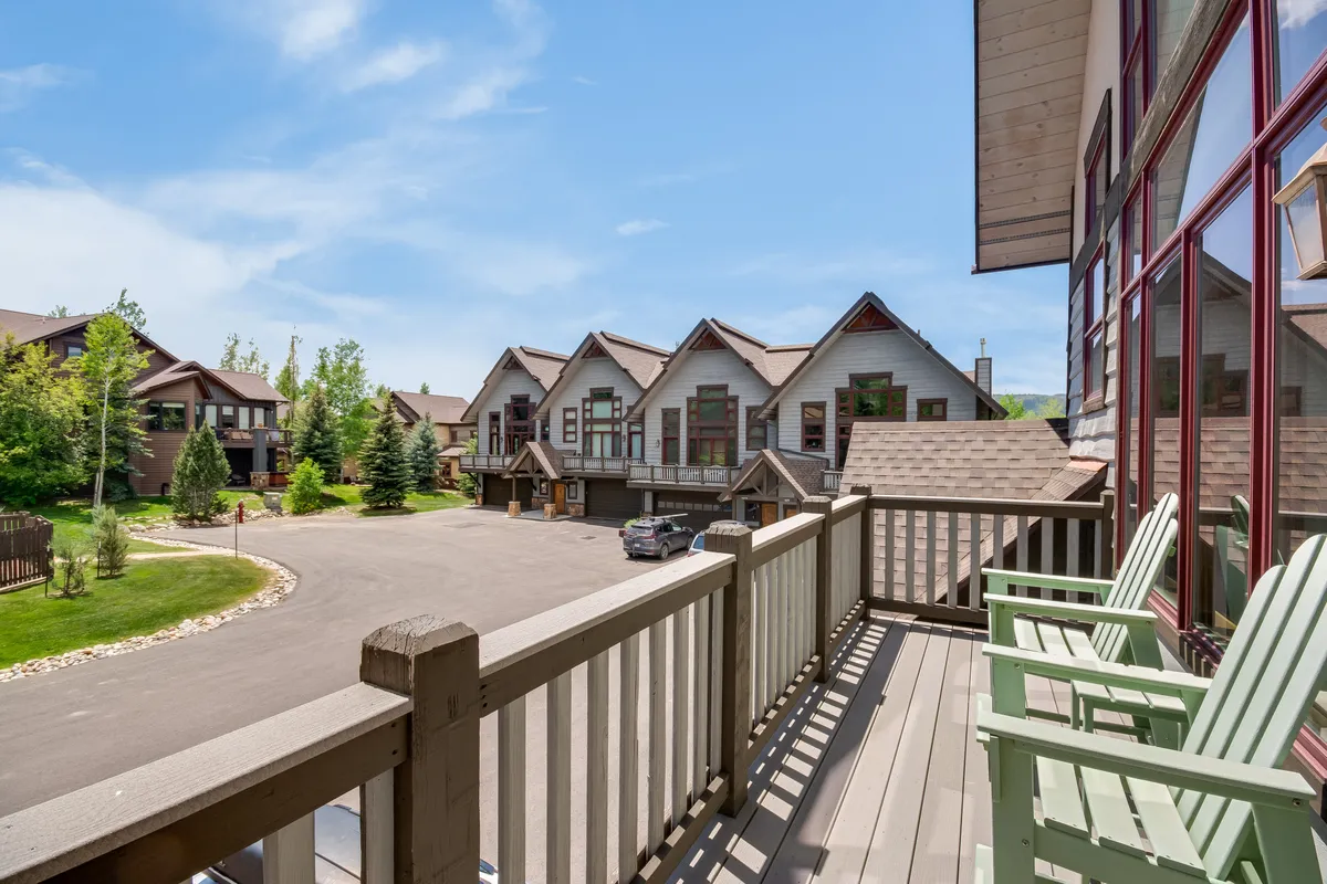 This exterior shot highlights balcony seating overlooking a landscaped garden, with neighboring buildings in the background. The tranquil scene suggests a welcoming outdoor space perfect for relaxing after a day of adventure.