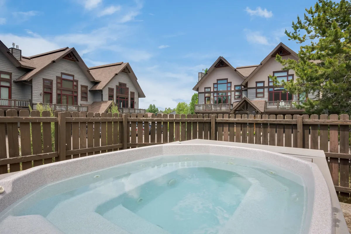 This exterior shot captures the inviting community hot tub framed by surrounding houses and a wooden fence. Steaming water beckons guests after a day on the slopes, while the open sky hints at relaxation under the stars.